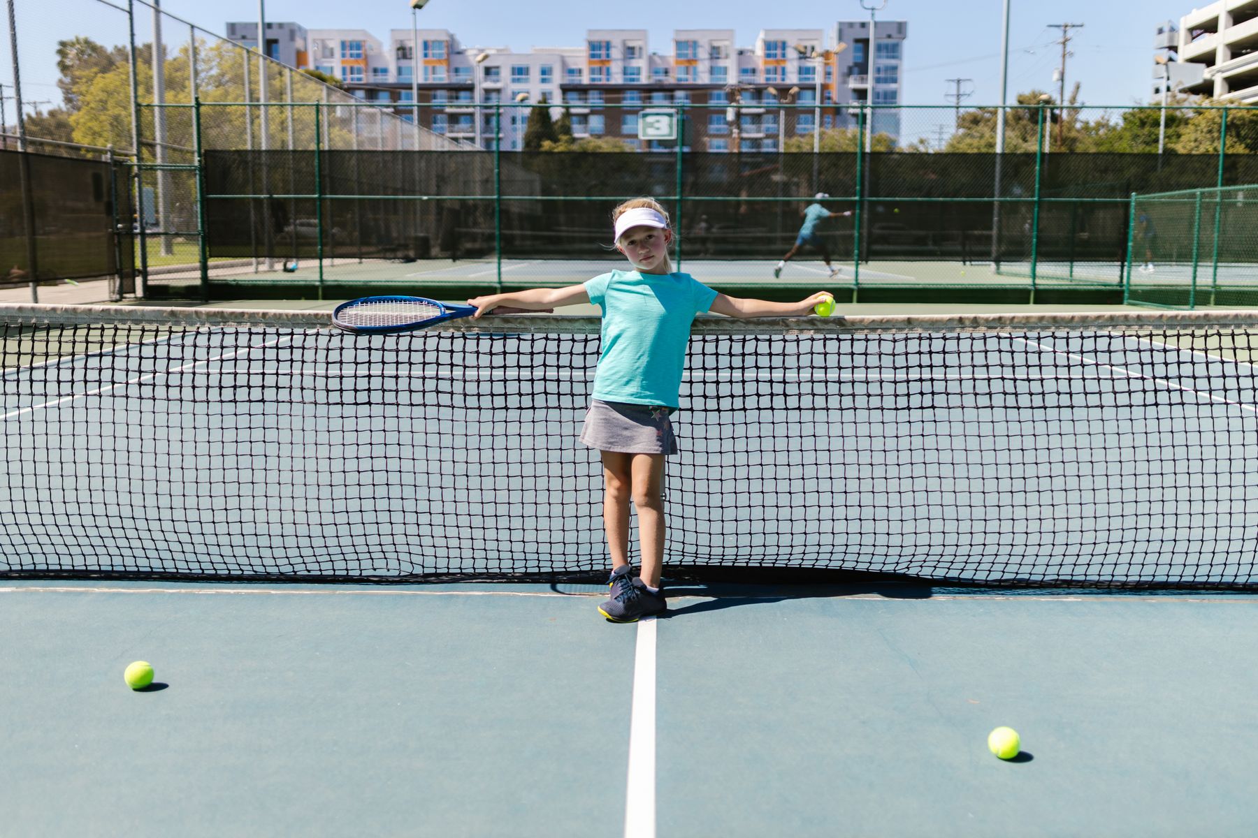 Young player smiling at the net during a junior tennis lesson