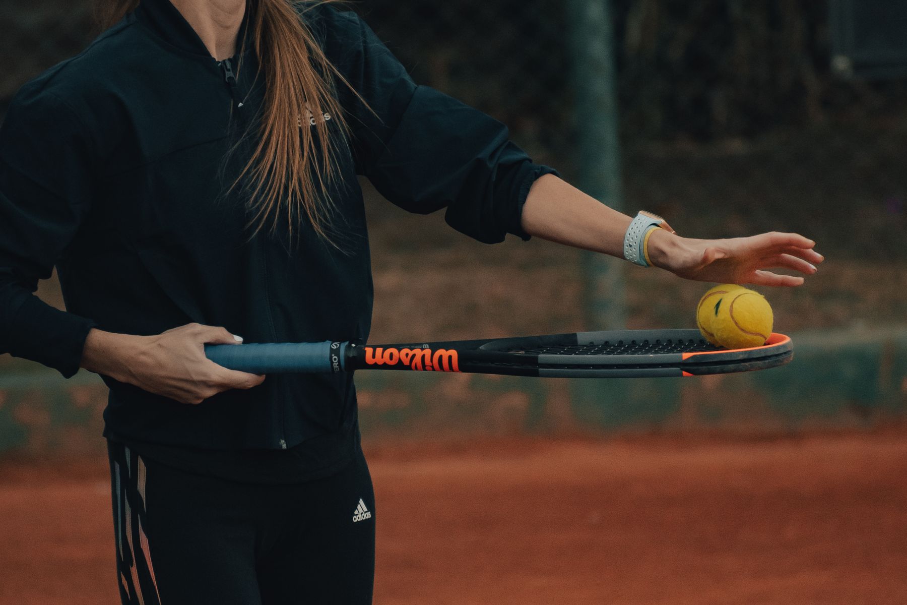 Coach holding a racquet and ball while setting up a feeding drill